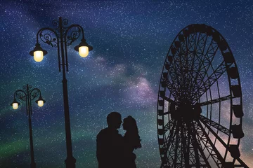 Deurstickers Lovers in amusement park at night. Vector illustration with silhouette of loving couple under starry sky. Vintage lampposts and Ferris wheel © arvitalya