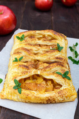 Layer pie with apples and cinnamon on a dark wooden background. Vertical view