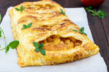 Layer pie with apples and cinnamon on a dark wooden background.