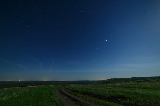 Night starry sky above the road in the countryside.