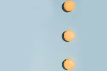 Three sweet yellow macaroons on blue table background.