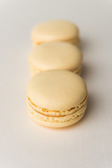 Sweet yellow macaroons on white table background.