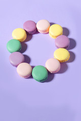 Sweet colorful macaroons on purple table background.
