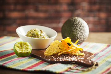 Guacamole on a wooden table with bricks background