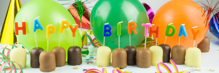 Happy Birthday, viele kleine Schaumküsse mit Geburtstagskerzen und Luftballons, Konfetti und...