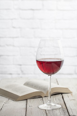 Wine glass and book in a white wooden table