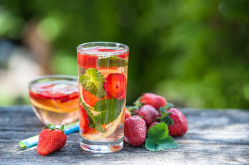 A glass of detox water. Strawberry, lemon and mint with cool clean water, backdrop of a green garden. Detox, diet, Cookery, sports, proper nutrition, sports nutrition, body cleansing
