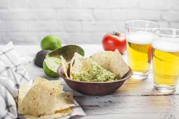 Homemade guacamole with corn nachos and a glasses of beer