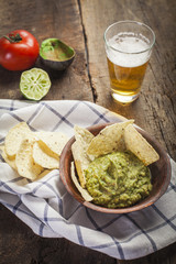 Homemade guacamole with corn nachos and a glasses of beer