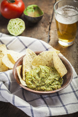 Homemade guacamole with corn nachos and a glasses of beer