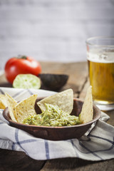 Homemade guacamole with corn nachos and a glasses of beer