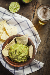 Homemade guacamole with corn nachos and a glasses of beer