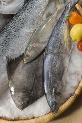 mix fresh fish on bamboo round tray with fresh vegetables with ice on brown background