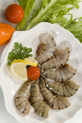 Jumbo headless shrimps with lemon and cherry tomato on white plate