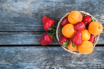 Basket  strawberries apricots, natural wood background. Fresh fruit and berries. Detox, diet,...