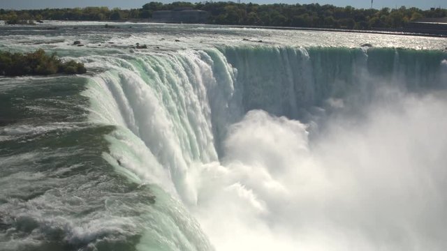AERIAL CLOSE UP: Flying above scenic Niagara Falls along the rocky edge where the whitewater rapids break and crush into the bottom of the waterfall. Thick fresh mist rising above the Horseshoe Falls