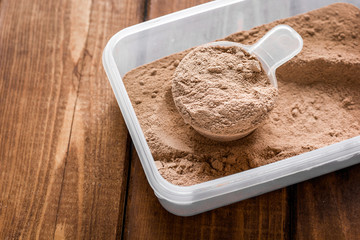 Fitness nutrition with scoop on wooden background