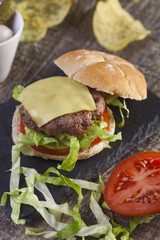 Homemade beef burger with tomato, lettuce and cheddar cheese on a wooden table 