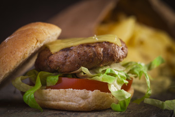Homemade beef burger with tomato, lettuce and cheddar cheese on a wooden table 