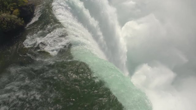 AERIAL CLOSE UP Flying above scenic Niagara Falls along the edge of a cliff. Whitewater rapids breaking and crushing into the bottom of the waterfall. Thick fresh mist rising above the Horseshoe Falls