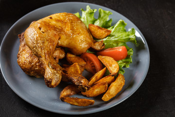 Roasted chicken legs with potato wedges and tomatoes