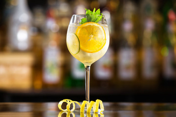 Closeup glass of white sparkling wine sangria decorated with citrus slices at bright bar counter...