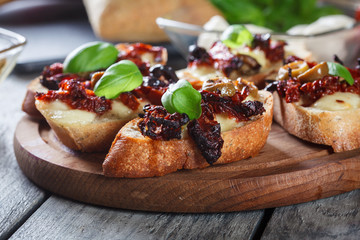 Appetizer bruschetta with sun-dried tomatoes, olives and mozarella.