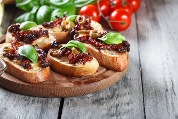 Appetizer bruschetta with sun-dried tomatoes, olives and mozarella.