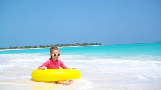 Adorable little girl with inflatable rubber circle splashing. Kid having fun on summer active vacation