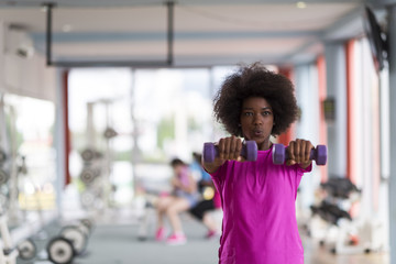 woman working out in a crossfit gym with dumbbells