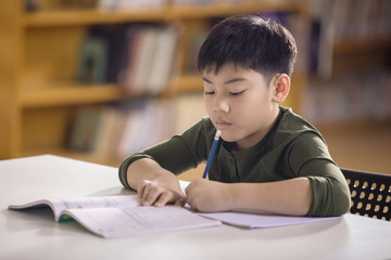 Happy asian child doing homework with smile face.