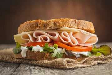 Wall murals Snack Tasty sandwich with ham, cheese, tomato and lettuce on wooden background