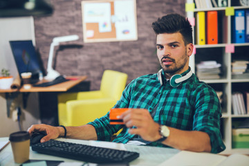 Man paying with credit card on computer at home office