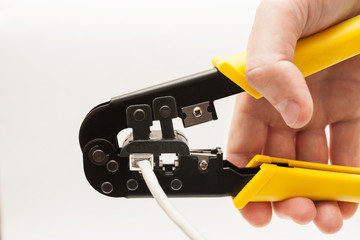 Crimp tool in hand on white background. Yellow crimping pliers closeup.