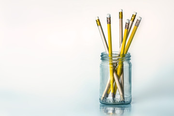 The golden yellow pencil in glass jar on white background with copy space , creative work idea or writing and drawing concept