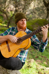 Hipster man with red beard playing a guitar