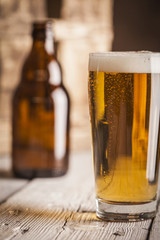 Bottle and glass of beer with wooden background