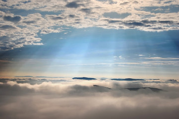 summer morning sun rays and fog covering hills