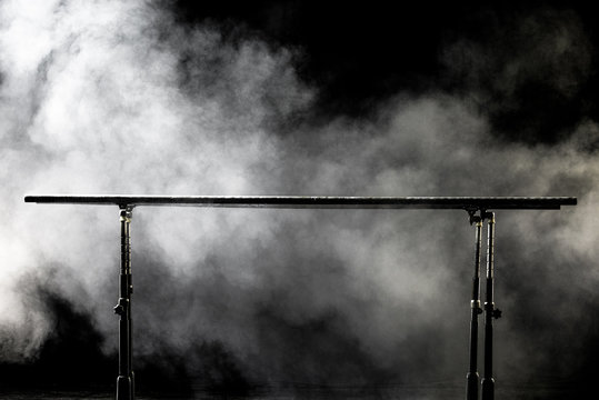 Closeup. Gymnastic parallel bars. Isolated on black background with fog,