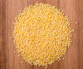 Round heap of millet groats on a wooden board. Top view, close up.
