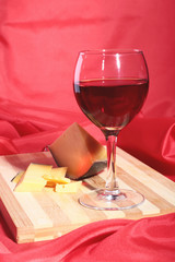 Bottle and Glass with red wine grapes and chees on wooden table.