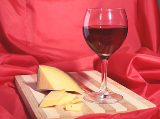 Bottle and Glass with red wine grapes and chees on wooden table.