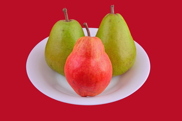 Pears on white plate on red background