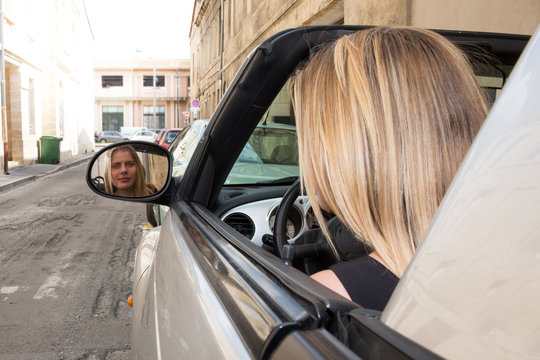 blond girl in the mirror of her car