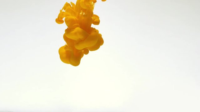 Yellow paint drop spreading in water slow motion