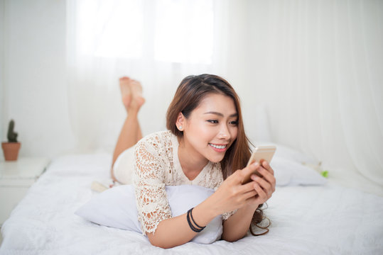 Woman Relaxing in bed and using mobile phone, relaxing in her living room