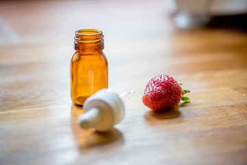 Pipette, medical bottle and strawberry on a wooden table