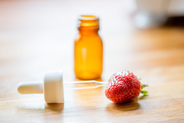 Pipette, medical bottle and strawberry on a wooden table