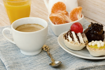 Cup of tea with milk, cute sweet cake, orange juice and fruit on wooden background. Good morning surprise concept. Vintage filter.