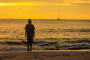 Silhouette boy walking on the beach during sunset at Koh Lanta Krabi Thaialnd